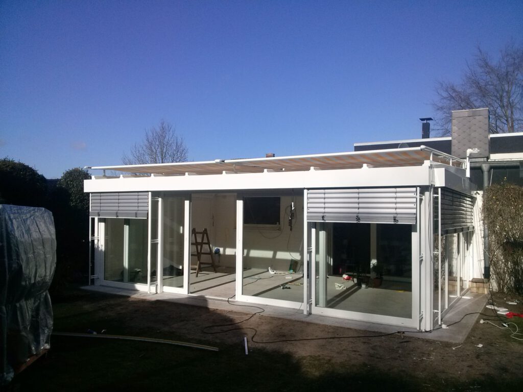 Moderner weißer Wintergarten mit großen Glasfronten und Sonnenschutz